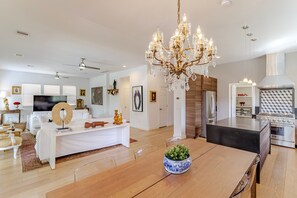 A modern living room with a dining area, a chandelier, and a kitchen with a stove. - Cozy House Retreat Near Texas Medical Center. (Houston)