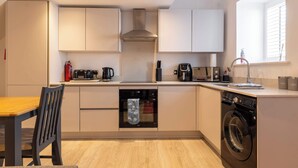 Una cucina compatta con forno, lavastoviglie e macchina da caffè.