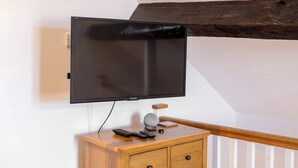 Un televisore montato a parete, un mobile in legno con un telecomando e una struttura portante in legno.