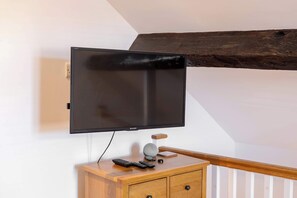A television mounted on a wall, a wooden cabinet with a remote control, and a wooden beam structure. - Cosy 1 bed close to Chester, parking! (Cheshire West and Chester)