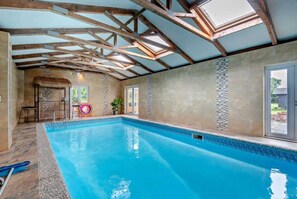 Una piscina con bordo piastrellato, travi in legno e copertura in paglia.
