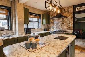 Una cucina con piano di lavoro in marmo, piano cottura integrato e zoccolo decorativo.