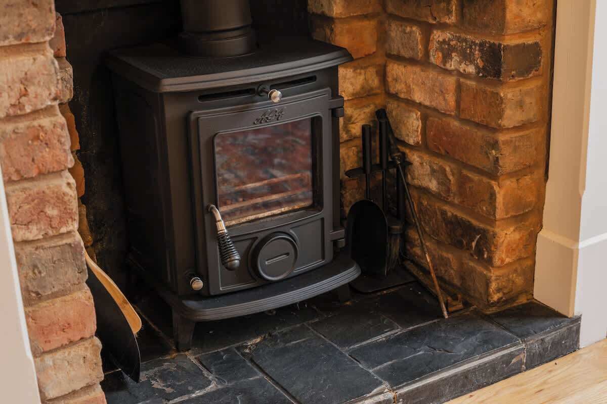 A wood-burning stove in a fireplace, a brick wall, and a stone floor.