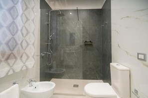 Ein modernes Badezimmer mit einer Duschkabine, einem Bidet und einer Toilette.