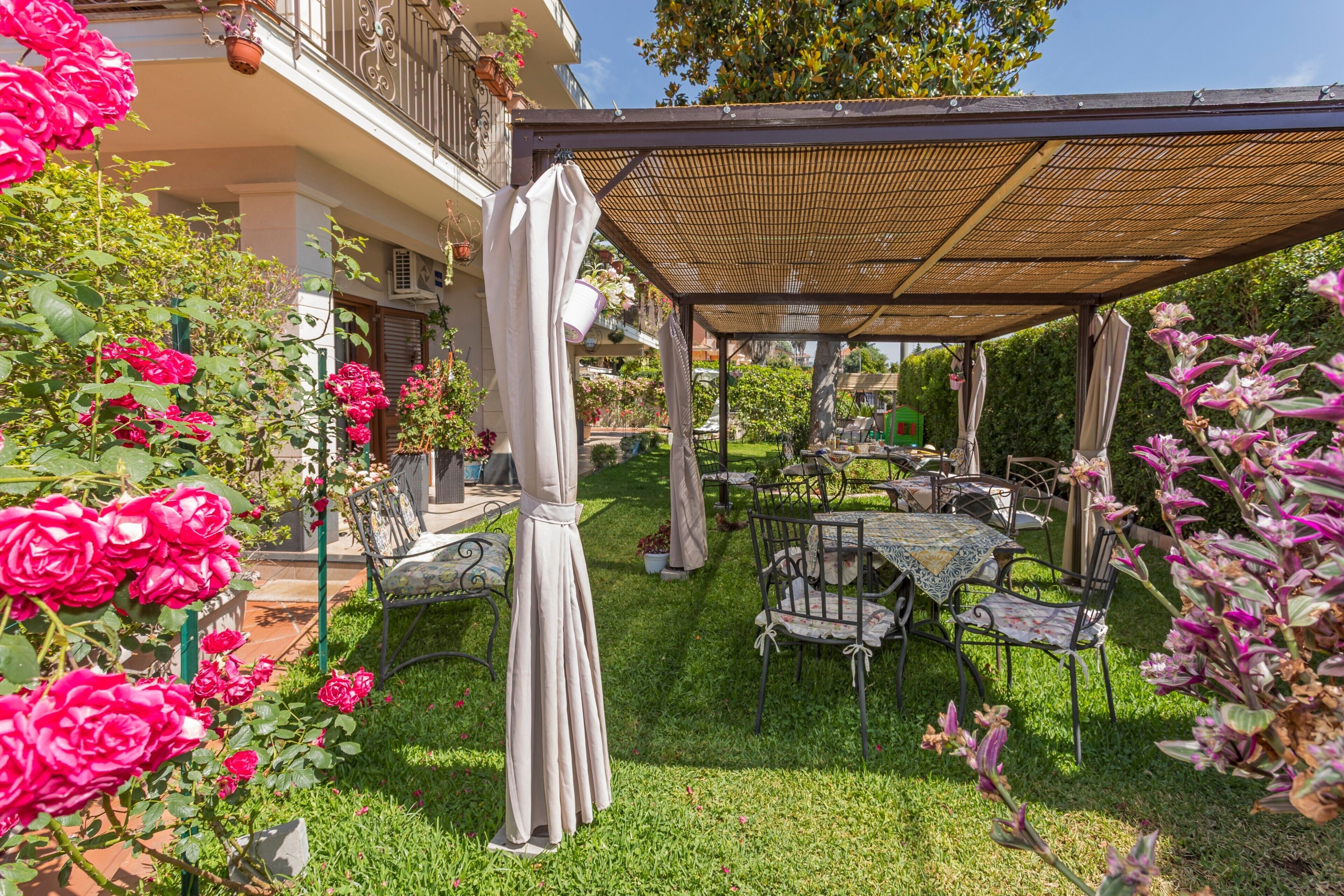 Een tuinpatio met buitenmeubilair, een pergola en weelderige beplanting.