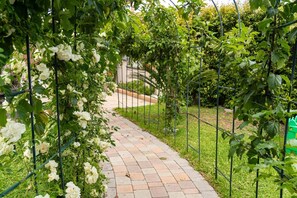 Un sendero en un jardín con cerca de metal y plantas trepadoras.