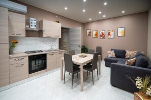 Una cocina moderna con una mesa de comedor y sillas, un sofá, y una pared decorada con cuadros.