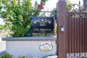 Ein begrenzter Eingangsbereich mit einem Schild für 'Villa Marchese' und einer dekorativen Plakette.