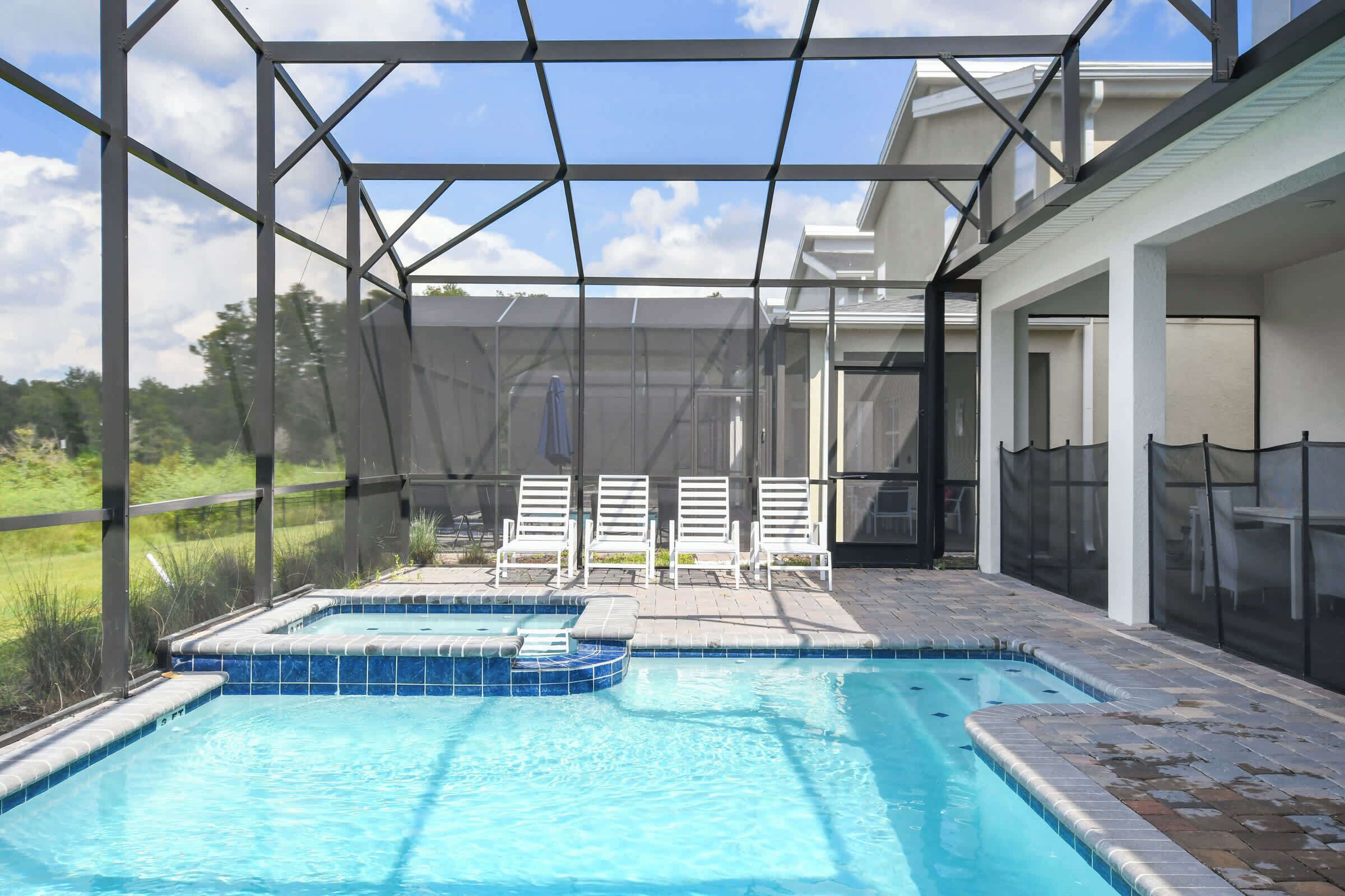 A pool area with a covered patio, lounge chairs, and a view of the surrounding landscape.