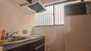 Una cocina compacta con microondas, lavamanos y una ventana pequeña.