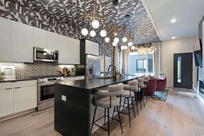 A modern kitchen with a central island, bar stools, and pendant lighting. - Modern 4BR Escape|Hot Tub, Sauna&Pool! Game Room! 11 beds! (Nashville)
