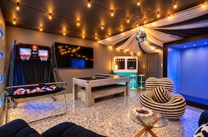 A room with a pool table, foosball table, and a ping pong table. There is a TV mounted on the wall and a disco ball hanging from the ceiling. - Music City Escape w/Rooftop Hot Tub & Pool! 11 Beds (Nashville)