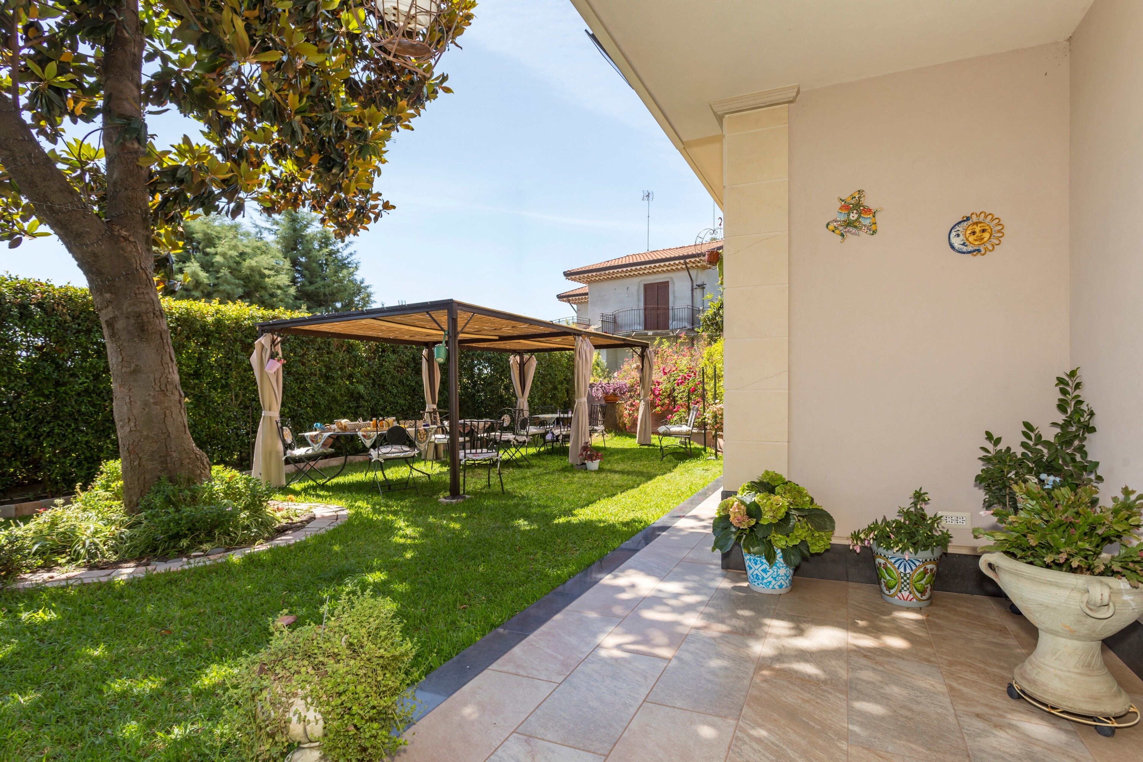 Eine Terrasse mit einer Pergola, Gartenmöbeln und Topfpflanzen.