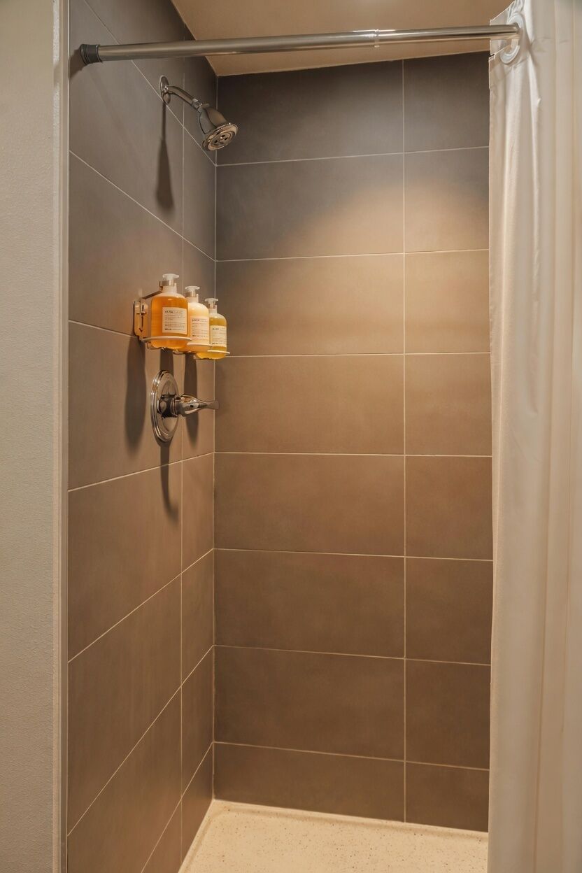 A shower with a glass door, a towel rack, and a shelf with toiletries.