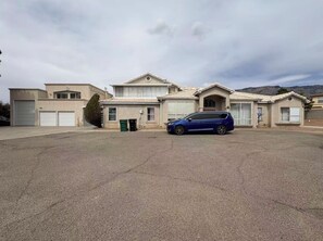 A large building with multiple garage doors, a blue car parked in front, and a clear sky.