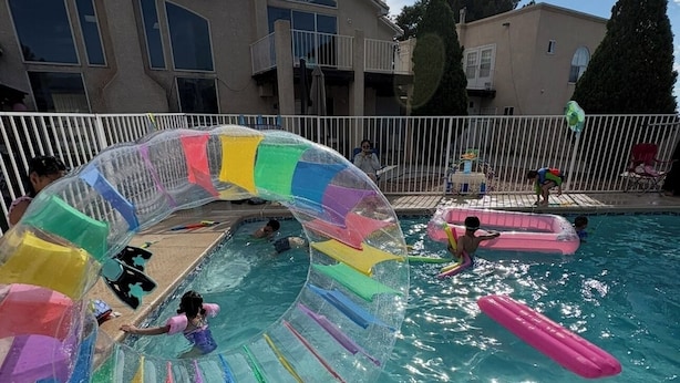 Una piscina con un tobogán de colores y juguetes inflables.
