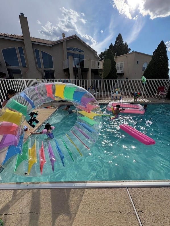 A swimming pool with a colorful water slide and inflatable rings.