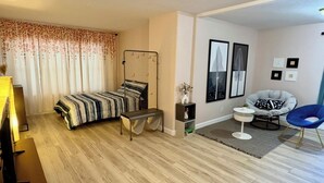 Un dormitorio moderno con cama, mesita de noche, silla y una obra de arte en la pared.