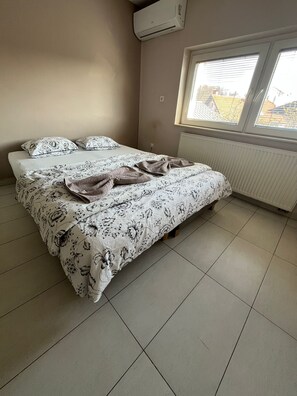 Un dormitorio con cama, ventana y aire acondicionado.