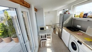 Una cocina compacta con lavadora, refrigerador y comedor con mesa y sillas.