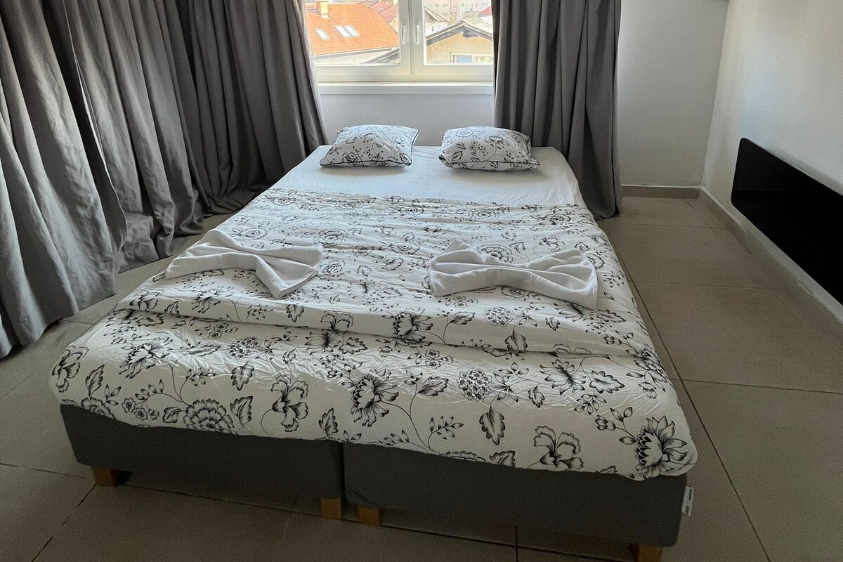 Un dormitorio con cama, cortinas, ventana y unidad de aire acondicionado.