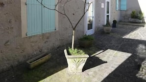 Een gebouw met een stenen gevel, een kleine boom en een plant in pot.