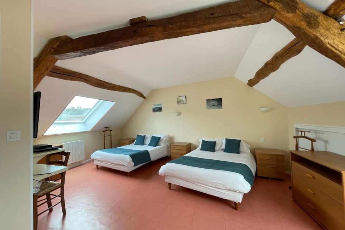 Ein Schlafzimmer mit zwei Betten, einem Schreibtisch, einem Stuhl und einer Kommode.