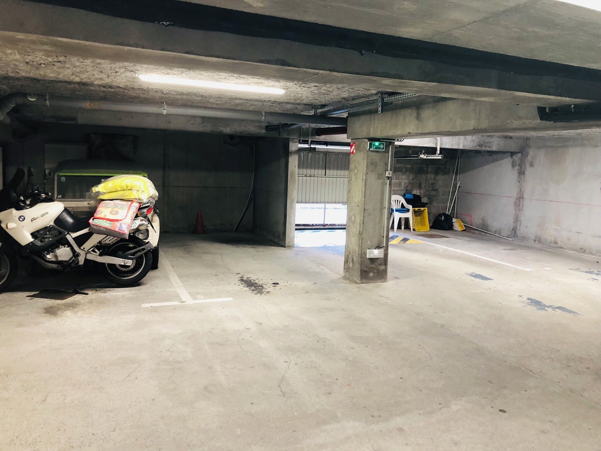 Een parkeergarage met betonnen pilaren, een motor en een stoel.