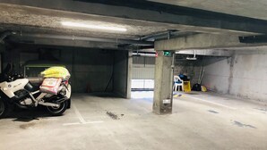 Uma garagem de estacionamento com pilares de concreto, uma motocicleta e uma cadeira.