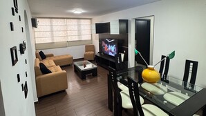 Un soggiorno con divano, tavolino, televisione e zona pranzo con sedie e tavolo.