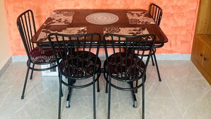 Un comedor con una mesa y sillas, un mantel estampado y una pared naranja con textura.