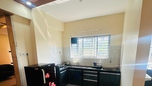 Una cocina moderna con refrigerador negro, electrodomésticos de acero inoxidable y un ventanal con barrotes.