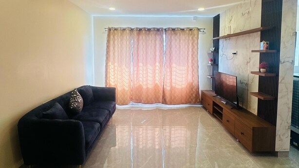 Sala de estar con sofá, televisor, mueble de entretenimiento y ventilador de techo.