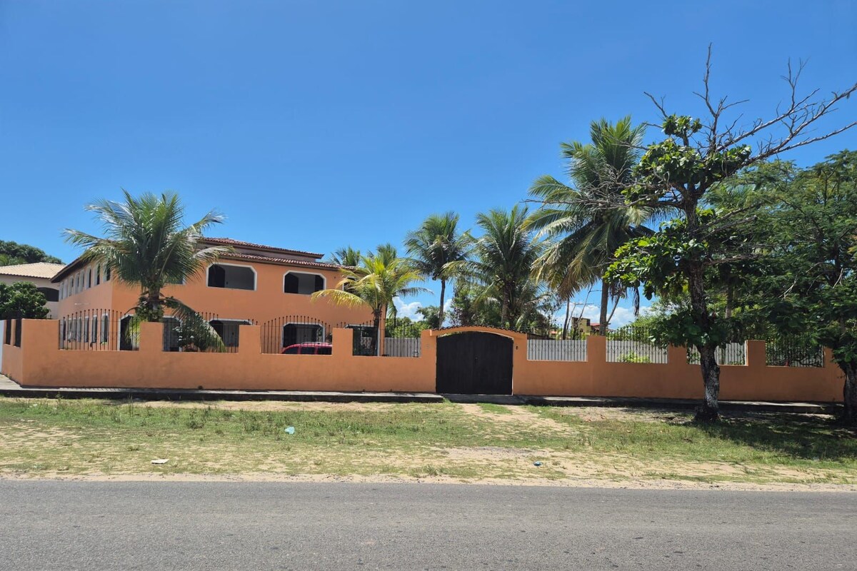 Un edificio de dos pisos con fachada marrón, entrada protegida por una reja y cielo despejado.