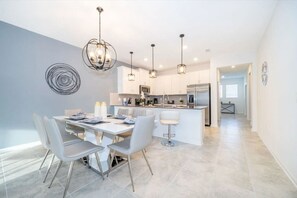 A modern kitchen with white cabinets, stainless steel appliances, and pendant lighting. - Magic Awaits: Modern 3BR Family Retreat (Kissimmee)