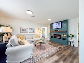 A living room with a sofa, coffee table, TV, fireplace, and decorative lamps.