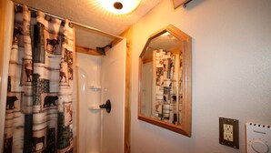 A bathroom with a shower curtain featuring animal prints, a mirror, and a wall-mounted thermostat. - Duck Pond Room, kitchenette, Restmore Inn, 2 miles to Hill City (Custer)