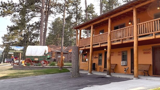 A two-story log cabin with a balcony, a porch with benches, and a sign indicating 'Pheasant Brews.' - Duck Pond Room, kitchenette, Restmore Inn, 2 miles to Hill City (Custer)