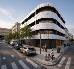 A modern building with a curved facade, multiple balconies, and a pedestrian crossing. - Skygate Lisbon Airport (Loures)