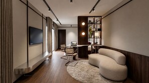 Ein modernes Wohnzimmer mit Flachbildfernseher, einer Couch, einem Essbereich mit Tisch und Stühlen sowie einem Holzregal.