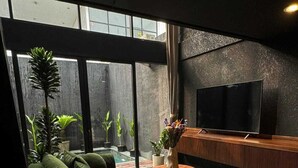 Ein modernes Wohnzimmer mit einem grünen Sofa, einem Fernseher und großen Fenstern.