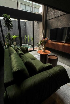 Una sala de estar moderna con un sofá verde, un televisor de pantalla plana y plantas en macetas.