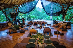 Ein Yoga-Kurs in einer Zelthalle mit Holzboden, Yogamatten und einem Tisch mit floraler Dekoration.