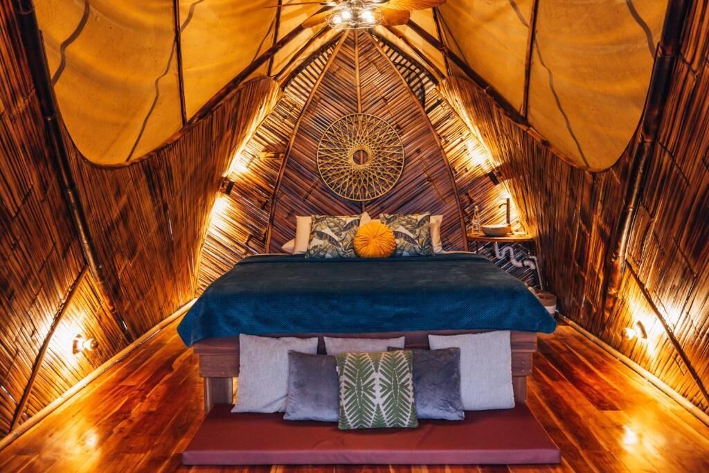A tent-style room with a bed, pillows, and a decorative wall pattern.