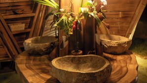 A rustic wooden table with a stone basin, a potted plant, and hanging light bulbs. - Qasa Boutique Hotel and Retreats - LGBTQ (Barú)