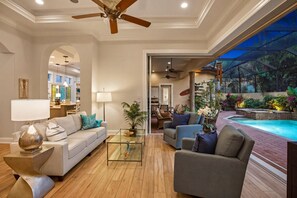 Ein geräumiges Wohnzimmer mit einem Glastisch, Sofas und einem Deckenventilator.