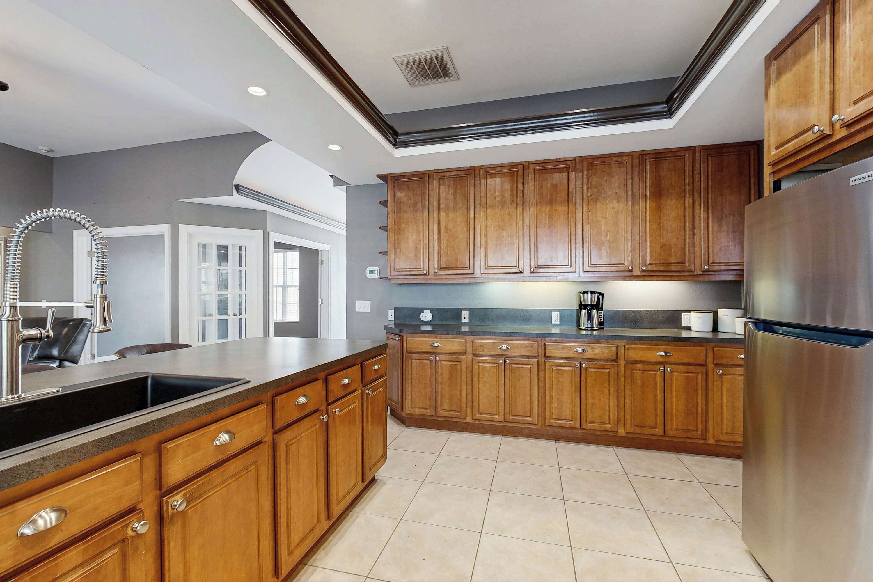 A kitchen with wooden cabinets, a stainless steel refrigerator, and a sink.