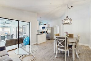 A modern kitchen with a dining area, large glass sliding doors, and a hanging light fixture. - Port Charlotte Oasis Private Pool Home with Spacious Kitchen (Port Charlotte)