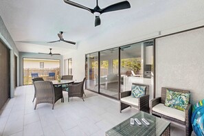 A spacious patio with a dining area, wicker furniture, ceiling fans, and a glass door leading to an outdoor space. - Port Charlotte Oasis Private Pool Home with Spacious Kitchen (Port Charlotte)