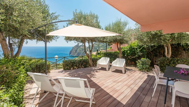 A wooden deck with white chairs and a table, overlooking a coastal view. - Apartment 'Paradise Residence 1' with Sea View, Wi-Fi and Air Conditioning (Sant'Alessio Village)